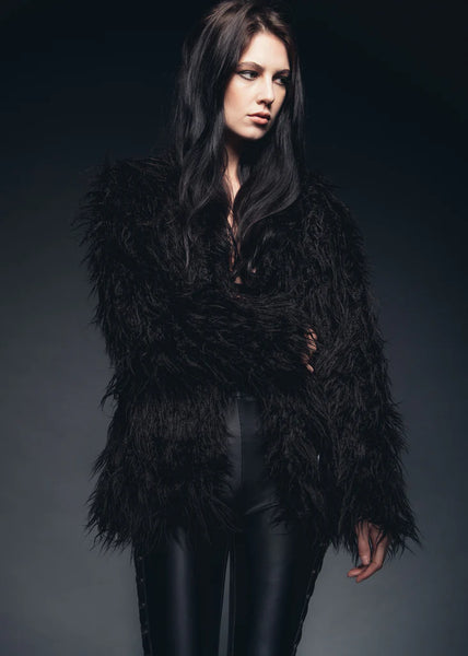 Woman wearing a black feathered jacket against a dark background