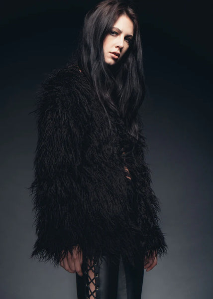Woman wearing a black feathered coat against a dark background