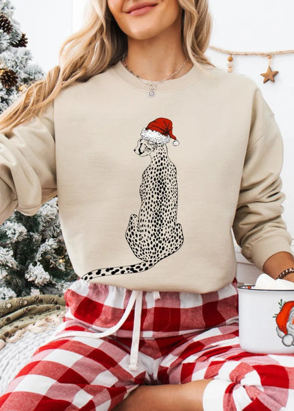 Person wearing a beige sweatshirt with a Christmas-themed design, sitting by a Christmas tree.